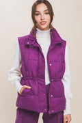 Woman wearing a purple puffer vest over a white turtleneck sweater